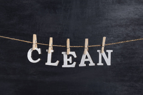 Word CLEAN hängt an Wäscheklammern vor schwarzem Hintergrund - Foto, Bild
