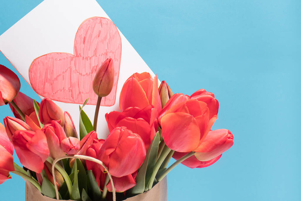 Красивая открытка с тюльпанами и открыткой красное сердце с местом для копирования текста cpace. На праздник 14 февраля, День Святого Валентина, День матери. - Фото, изображение
