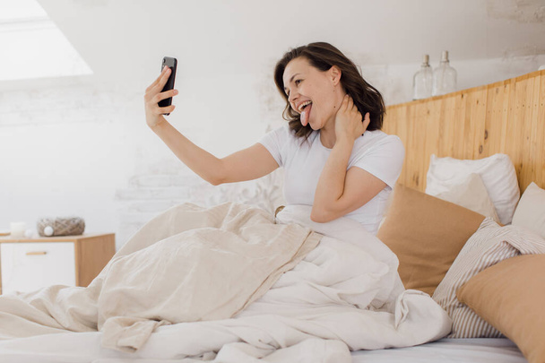 young attractive woman takes a selfie just after waking up - Fotografie, Obrázek