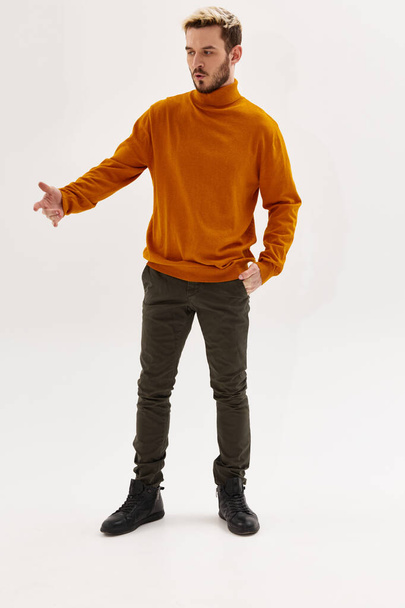 a man in a full length sweater gestures with his hands fashionable hairstyle for lifestyle - Foto, Imagen