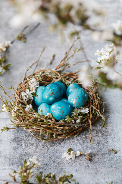 Easter eggs, feathers in a nest on a grey background. The minimal concept. Side view.  - Foto, afbeelding