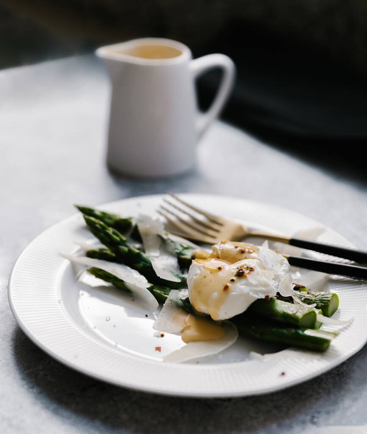 Green asparagus and boiled poached egg on a blue plate over a dark concrete background - Фото, зображення