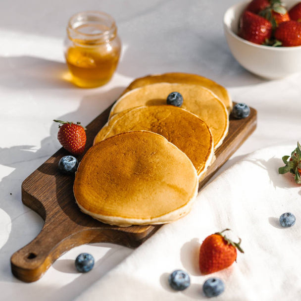 American pancakes on a wooden plate with light background - Fotó, kép