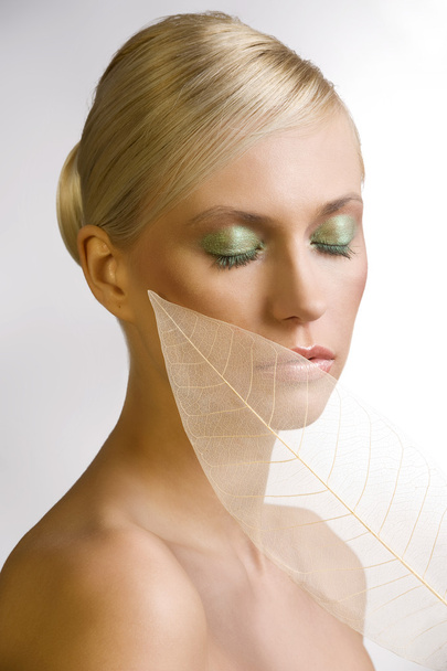 fashion beauty portrait of young beautiful woman with colored make up and a transparent leaf near her face - Foto, imagen