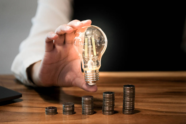 saving coins idea with light bulb for investment Concept idea and innovation - Photo, Image