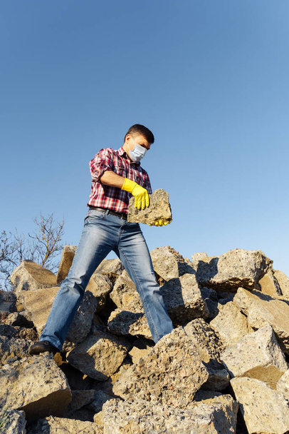 um homem trabalha com uma pilha de pedras e pedaços quebrados de concreto, carrega detritos de construção - Foto, Imagem