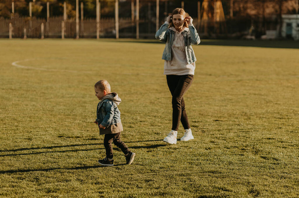 Счастливая семья веселится и бегает на свежем воздухе, мама и ребенок бегают в парке - Фото, изображение