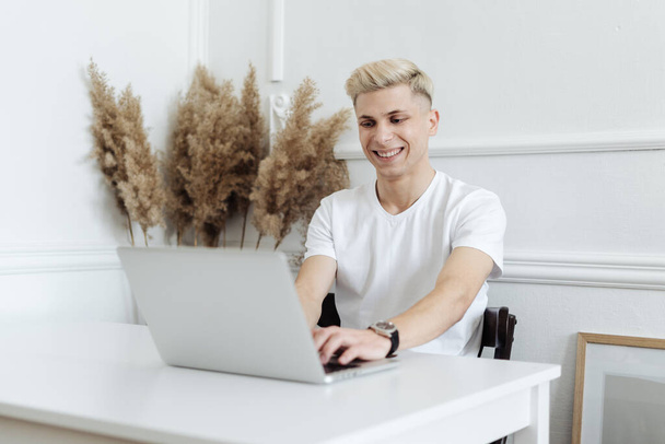 Man smiling working using computer laptop in a white space - Фото, изображение