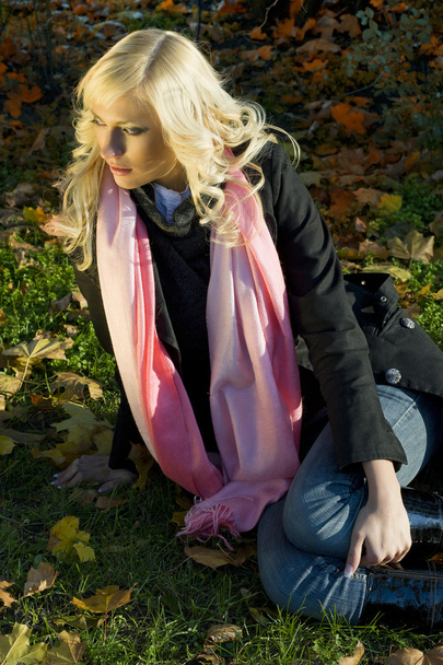 warm and fashion portrait of blond model sitting on the grass in a sunny winter day with hair style - Foto, imagen