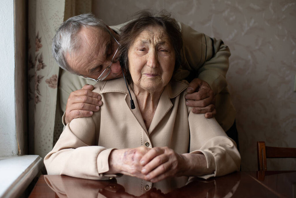 Seniorin bekommt einen Kuss von ihrem liebevollen erwachsenen Sohn, der sie im Pflegeheim besucht hat. - Foto, Bild