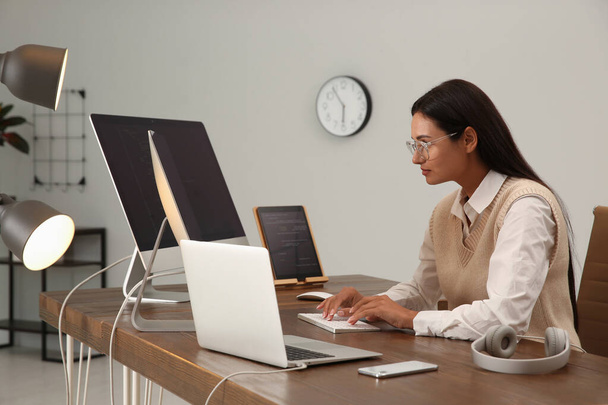 Programmer working at desk in modern office - Фото, изображение
