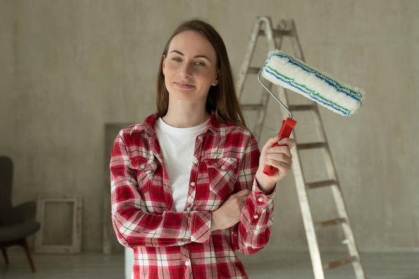 Kobieta maluje ściany w domu, trzyma wałek. Koncepcja naprawy i renowacji domu - Zdjęcie, obraz