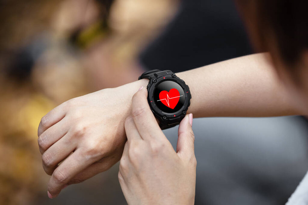 Digitale Armbanduhr mit Herzsymbolen, weibliche Herzfrequenzmessung in der Smartwatch. - Foto, Bild