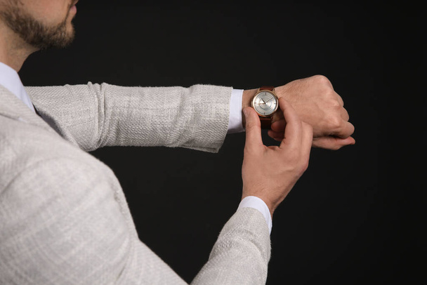 Businessman looking at wristwatch on black background, closeup. Time management - Foto, afbeelding