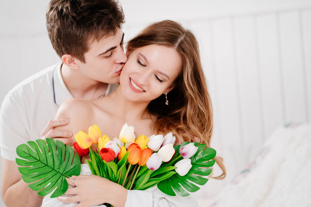a man gave his beloved woman a bouquet of colorful tulips. gentle kiss - Foto, Imagem