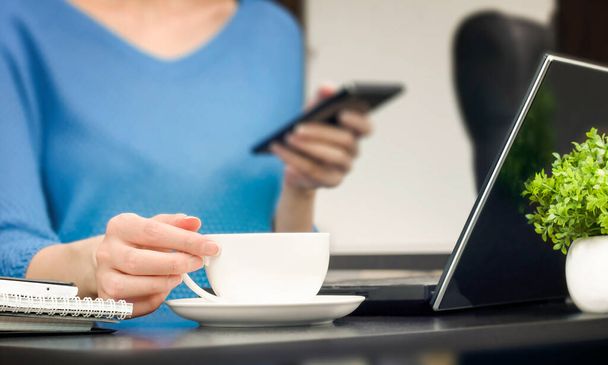 Женщина, сидящая за столом, работает и пьет кофе. внештатная концепция - Фото, изображение