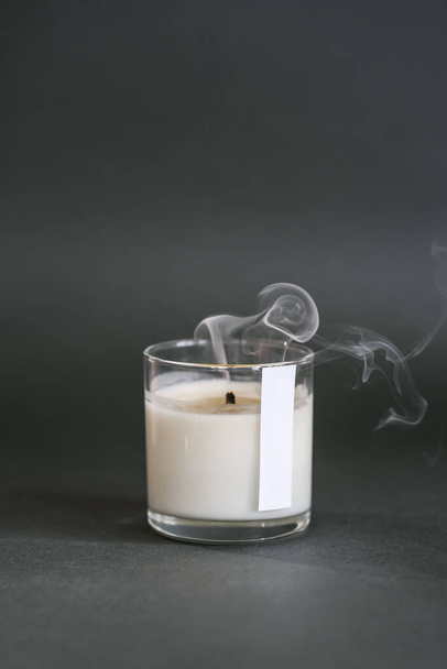 A smoking handmade candle on a dark background. - Foto, afbeelding