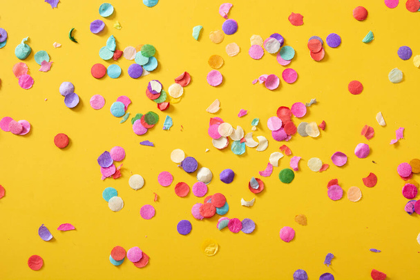 Colorful confetti on yellow background. - Photo, Image