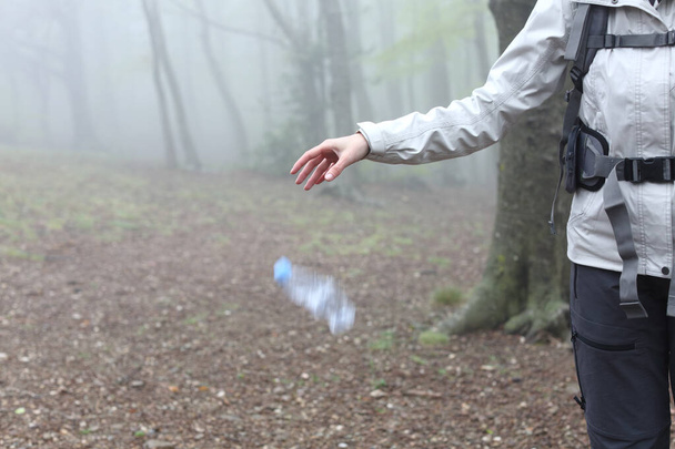 Close up of an uncivil trekker throwing garbage to the ground in nature - 写真・画像