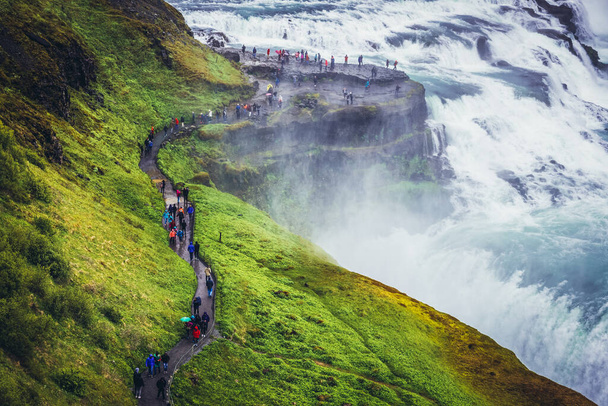 Southwest Iceland, Iceland - June 22, 2018: Tourists walks on a trail next to Gullfoss waterfall on the Hvita river - Foto, afbeelding