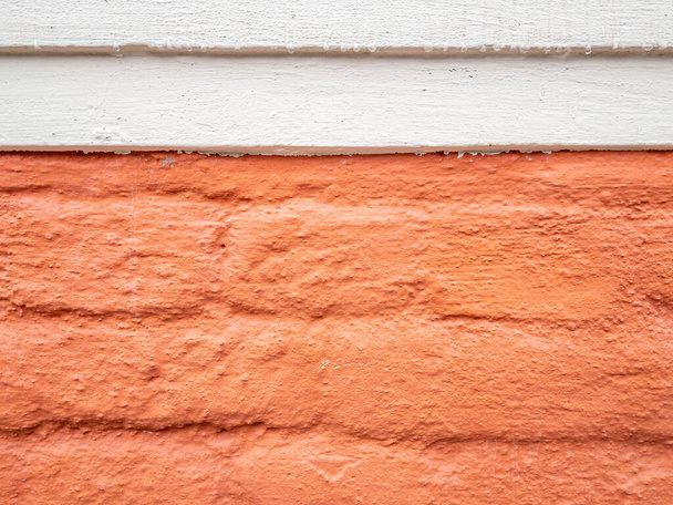 Stockholm, Sweden - April 22, 2021: Orange painted brick wall with white upper stripe on cloudy day with negative space - Photo, Image