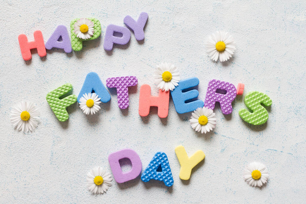 Lettering happy father's day. Father's day composition with colorful letters and daisies  - Photo, image