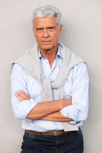 Retrato frontal de homem mais velho bonito com braços cruzados por parede branca  - Foto, Imagem
