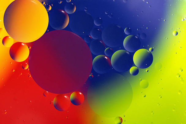 水面の水滴のマクロ写真。多色鮮やかな背景コズミックサークルは分子構造のように見えます。コピースペースのある背景、テンプレートとして良い. - 写真・画像