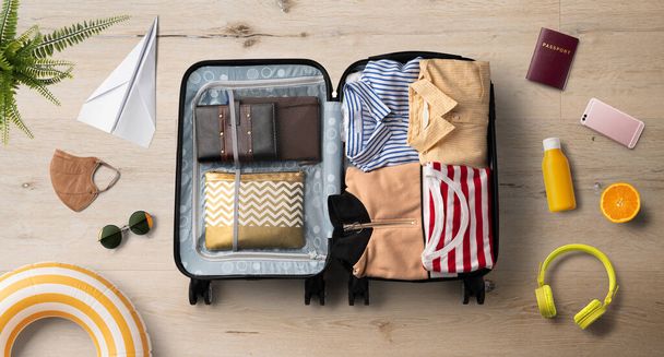 Flat lay top view of packed suitcase and travel essentials, summer holiday, coronavirus and new normal concept. - 写真・画像