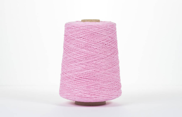 Close-up of a pink bobbin with cotton thread on a white background. - Foto, immagini