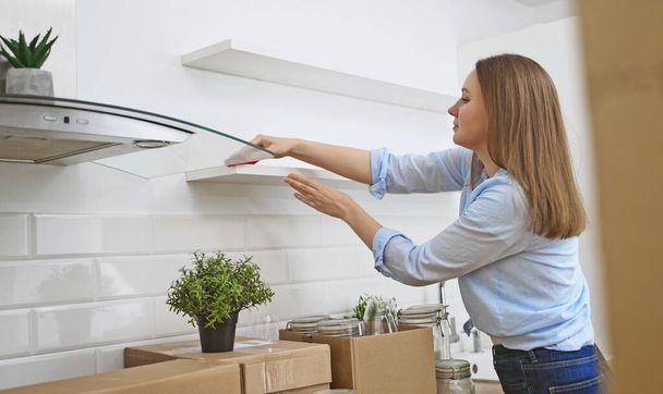 Mujer limpia la cocina después de mudarse a nuevo apartamento. - Foto, Imagen