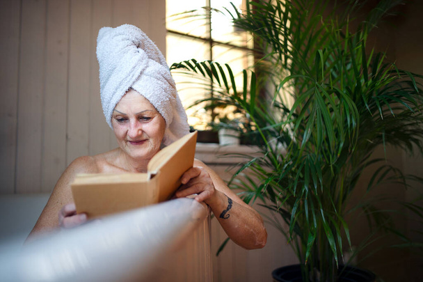 Glückliche Seniorin liest Buch zu Hause in Badewanne. - Foto, Bild