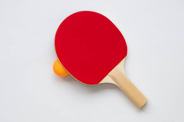 Tischtennisschläger auf weißem Hintergrund, mit orangefarbenem Tischtennisball. - Foto, Bild