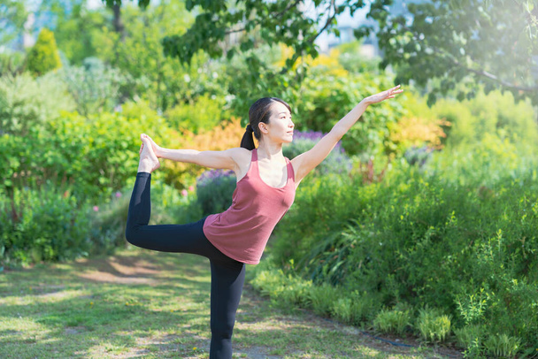 Młoda kobieta uprawia jogę w zielonym parku w piękny dzień - Zdjęcie, obraz
