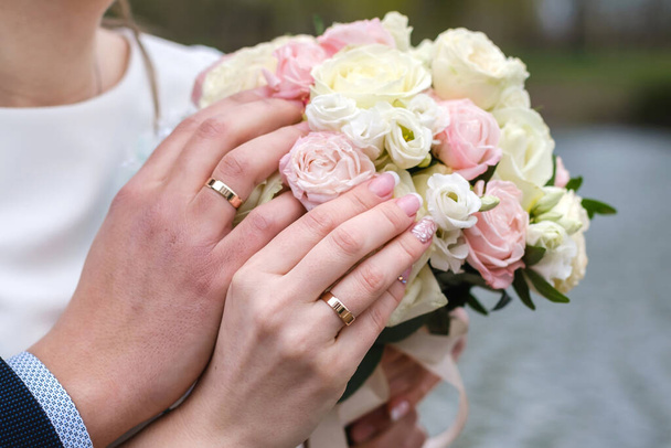 Nevěsta a ženich drží svatební kytici růží pohromadě. Svatební prsteny jsou na prstech. - Fotografie, Obrázek