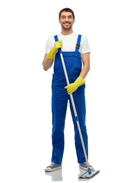male cleaner in overall cleaning floor with mop - 写真・画像