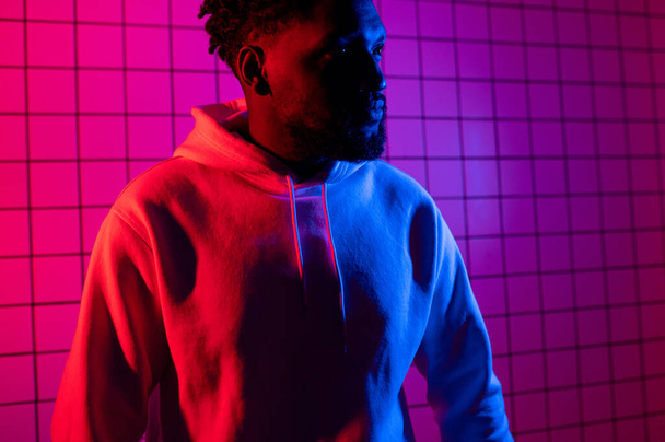 Portrait of an African American man in a hoodie on a neon background. Red-blue background. - Fotografie, Obrázek