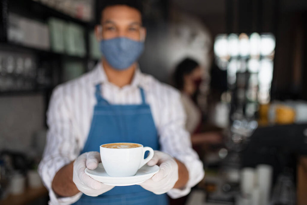Portrait of waiter serving coffee in cafe, small business, coronavirus and new normal concept. - 写真・画像
