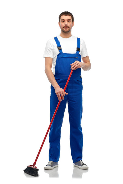 male cleaner in overall cleaning floor with broom - Foto, Bild