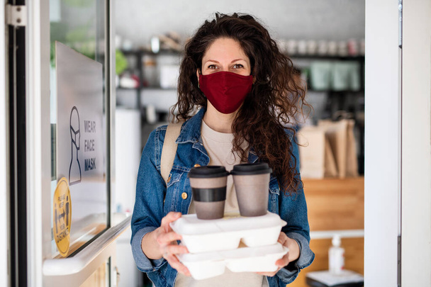Woman with packed take away food and coffee, looking at camera. Coronavirus concept. - Fotoğraf, Görsel