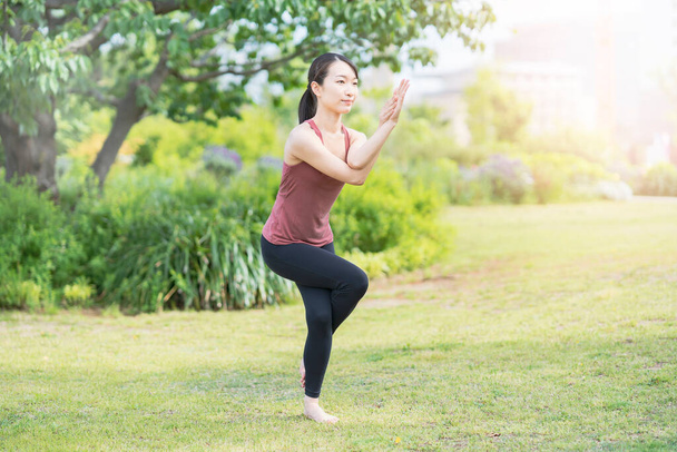 Mujer joven haciendo yoga en un parque verde en un buen día - Foto, imagen