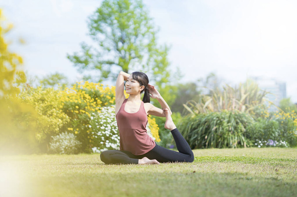 Mujer joven haciendo yoga en un parque verde en un buen día - Foto, imagen