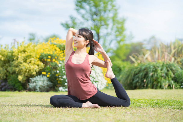 Mujer joven haciendo yoga en un parque verde en un buen día - Foto, Imagen