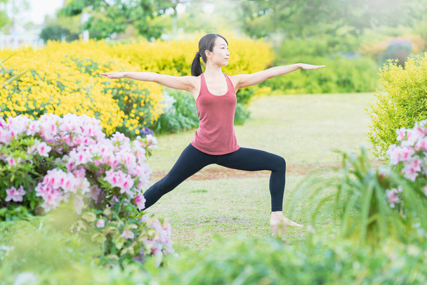 Yeşil bir parkta yoga yapan genç bir kadın. - Fotoğraf, Görsel