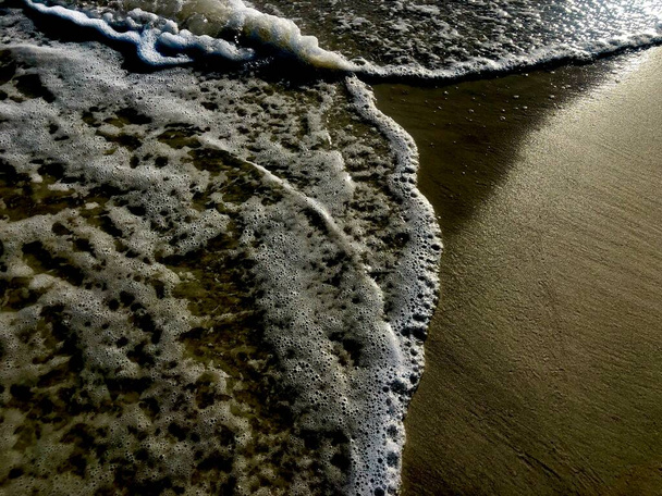 Primo piano di dolci onde oceaniche che rifluiscono e scorrono sulla sabbia  - Foto, immagini