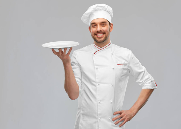 happy smiling male chef holding empty plate - Zdjęcie, obraz