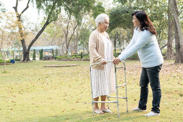 Asya 'lı yaşlı ve yaşlı kadınlara yardım ve yataklık etmek için parkta yürürken sağlıklı bir şekilde yürüyen yaşlı kadın kullanılıyor.. - Fotoğraf, Görsel