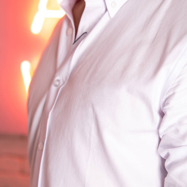 fehér férfi ing közelről a fehér téglafalhoz. - Fotó, kép
