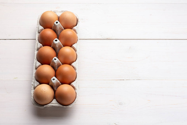 Fresh organic chicken eggs in carton pack or egg container  on white wood background. Space for text. - Foto, imagen