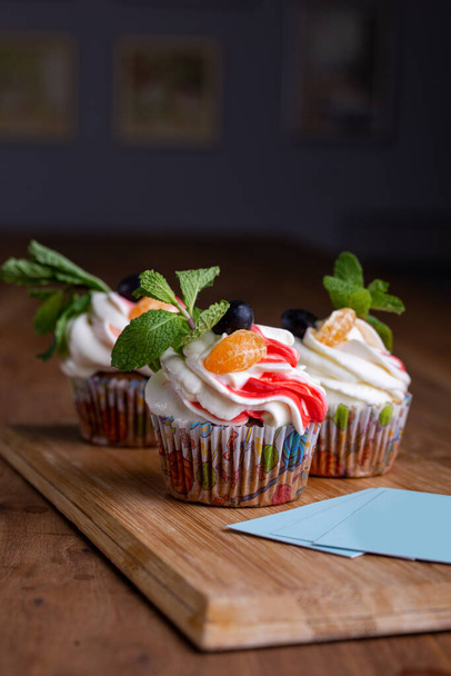 tre cupcake su uno sfondo di legno con biglietti da visita per il tuo design. - Foto, immagini